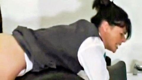 Mature lady in vest and shirt bent over exposing ass for caning punishment