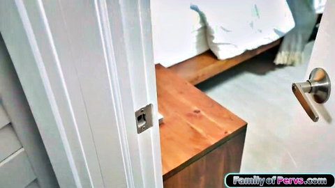 Voyeur peeking through cracked white door into empty bedroom with wooden bed and white pillow