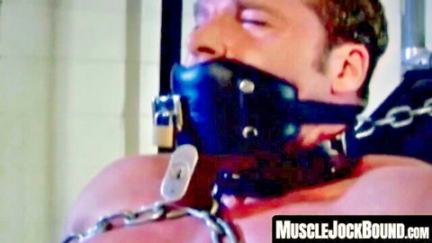 Muscular gay jock bound in black leather ball gag muzzle collar and chains for intense BDSM submission