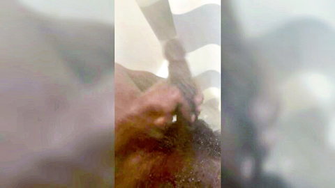 Blurry closeup of dark hand gripping thick black dildo amid white sheets