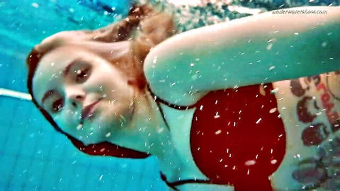 Beautiful redhead teen in black bra smiling underwater in pool