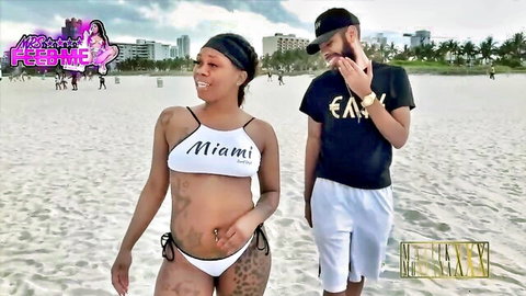 Mrsfeedme in skimpy Miami bikini on beach with fan, curvy pregnant body tattoos
