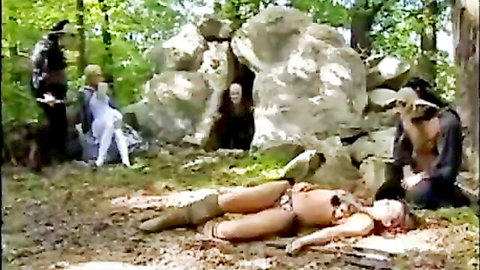Blonde babe in skimpy tribal outfit captured by cloaked men in forest ritual