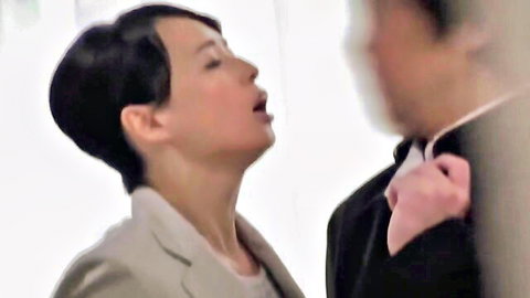 Japanese teacher in gray suit looks up mouth open at suited man in JAV seduction scene
