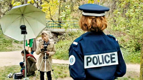 Lea Wiazemsky in police uniform on outdoor film set, back view