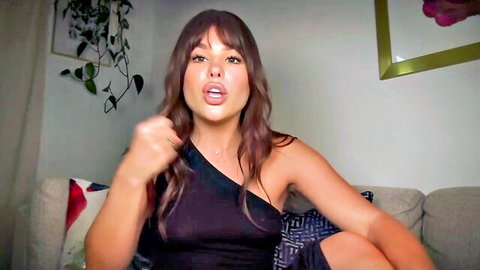 Brunette woman in black one-shoulder top gesturing excitedly, adult video thumbnail