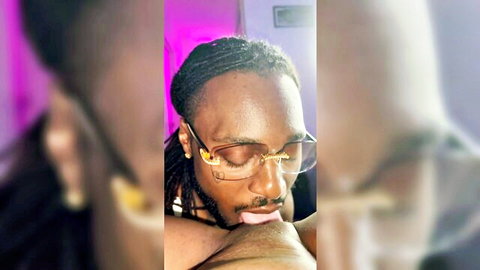Intimate close-up of Black man with dreads and glasses in oral pleasure scene