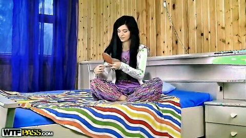 Greta A in cozy pajamas, sitting on bed reading phone, teasing encounter