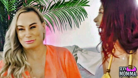 Blonde MILF in sheer orange robe stares seductively at sexy redhead in yellow top lesbian tease
