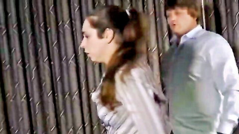 Brunette woman in striped blouse approached by man in sweater, spanking preview