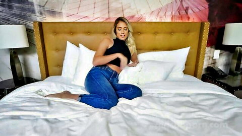 Blonde Athena Palomino teases on bed in black tank top and jeans