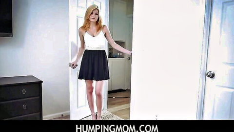 Blonde stepmom in white tank top and black mini skirt poses in doorway