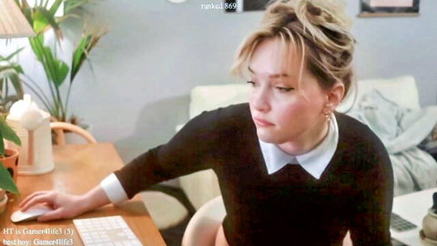 Blonde babe in black sweater and white collar sits pensively at desk hand on mouse in sensual webcam solo