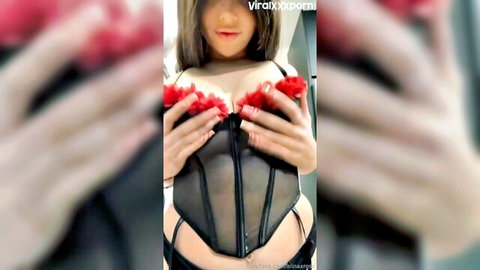 Alina Rose teasing in black mesh corset with red feathers, showcasing curves