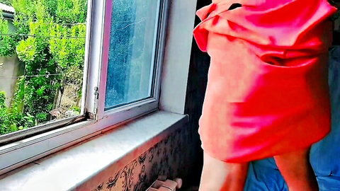 Crossdresser_kitty in flowing red dress posing by window