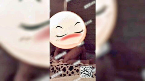 Blushing Korean girl with emoji filter close-up in dim bed setting
