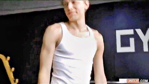 Athletic young Caucasian guy in white tank top at gym
