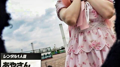 Pink-haired Japanese girl in frilly lolita dress posing outdoors