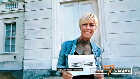 Blonde tattooed Lou Nesbit holding Wolf Wagner sign in teasing pose