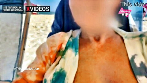 Busty Asian woman showing deep cleavage in open colorful shirt on beach
