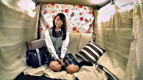 Cute Japanese schoolgirl in plaid skirt and vest smiling in tent, ready for panty handjob