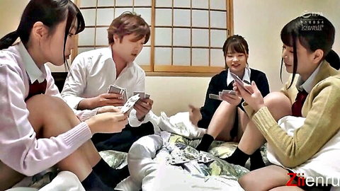 Japanese schoolgirls in uniforms playing cards with guy on bed