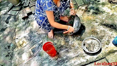 Desi village girl in blue dress squatting outdoors cooking