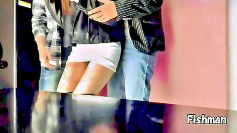 Asian woman in plaid shirt, leather jacket, and white mini skirt with man behind her