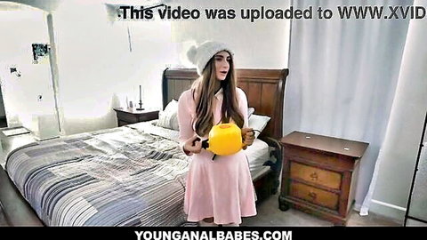 Penelope Kay in pink dress and beanie, holding yellow watering can, teasing pose