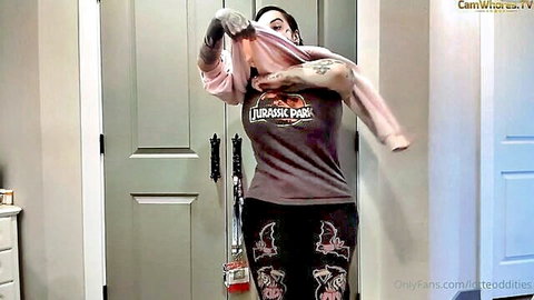 Goth woman with huge tits lifting Jurassic Park shirt to tease cleavage