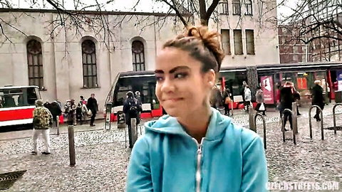 Busty gypsy woman in blue hoodie smiling on urban street