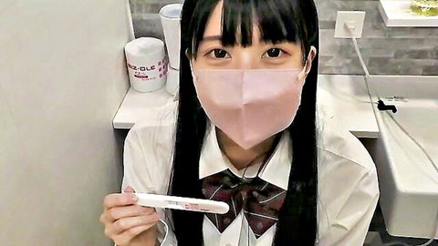 Japanese schoolgirl in uniform holding positive pregnancy test, wearing mask
