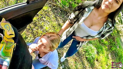 Blonde kneels sucking phallic toy outdoors as brunette watches, rock-paper-scissors dare