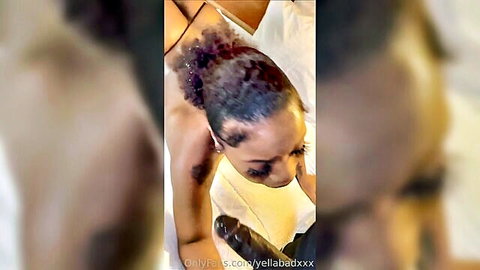 Ebony woman with curly hair sucking large black dildo in white lingerie