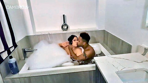 Interracial couple kissing in bubbly bathtub, passionate embrace