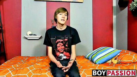 Young long-haired guy in black shirt interviewed on bed for sexy fun