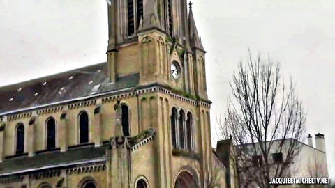 Snowy gothic church tower with clock and arched windows in winter landscape jacquemiche