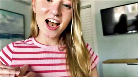 Gorgeous blonde teen seductress smiling with tongue piercing in striped top