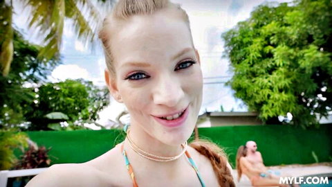 Blonde MILF in orange bikini smiles poolside for steamy foursome tease