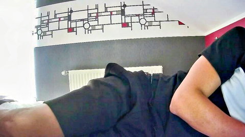 Gay amateur guy lying on bed with shorts pulled down exposing thighs