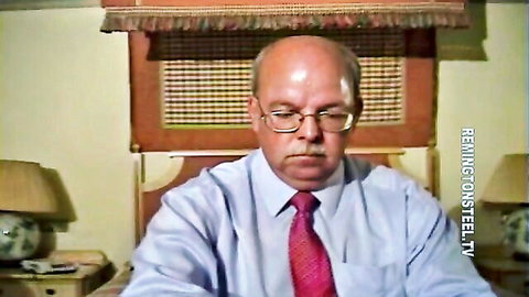 Bald mature man in glasses white shirt red tie sits seriously at office desk