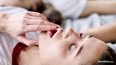 Sensual brunette inhales deeply, fingers to lips in intimate bedroom moment