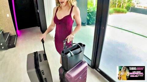 Busty blonde MILF in tight purple dress showing deep cleavage with luggage in luxury home