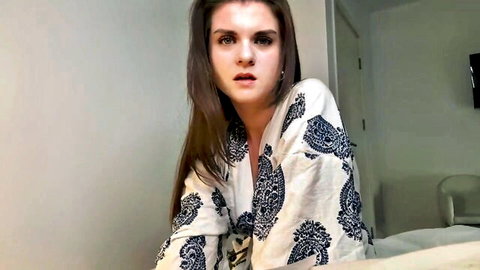 Surprised brunette stepmom in patterned robe on bed, caught moment
