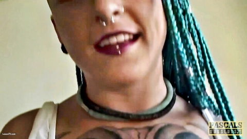 Teal-dreadlocked pierced tattooed babe smirks with open mouth and choker necklace