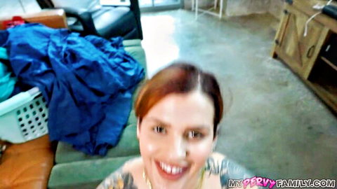 Tattooed redhead with big tits smiling topless in messy living room selfie