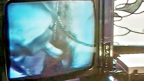 Vintage TV screen displays blurry femdom mistress in leather yanking chains on bound sub