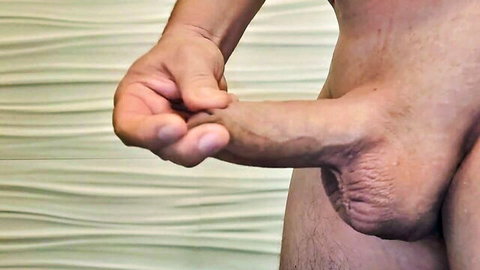Man's hand inserting 10mm Hegar dilator fully into erect penis for urethral sounding
