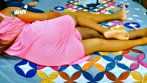 Tharudini in pink dotted dress, lying seductively on bed showing feet