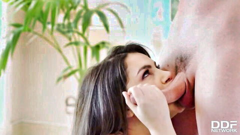 Brunette with curvy lips tongues thick cock while gripping shaft closeup